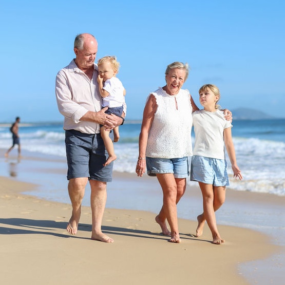 grandparent walking with grandchildren along thebeach